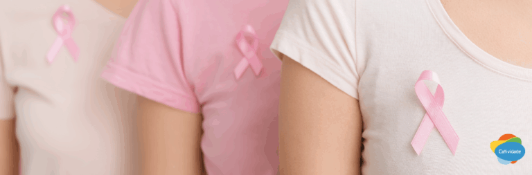 Grupo de colaboradoras vestindo rosa e segurando laços do Outubro Rosa, representando a cultura de cuidado e prevenção do câncer de mama no ambiente de trabalho.